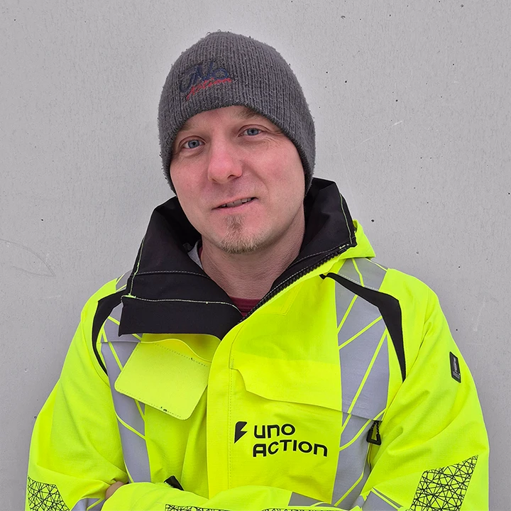 Teemu Salmelan henkilökuva, jossa hän katsoo hymyillen kameraan Uno Actionin työtakki päällään.