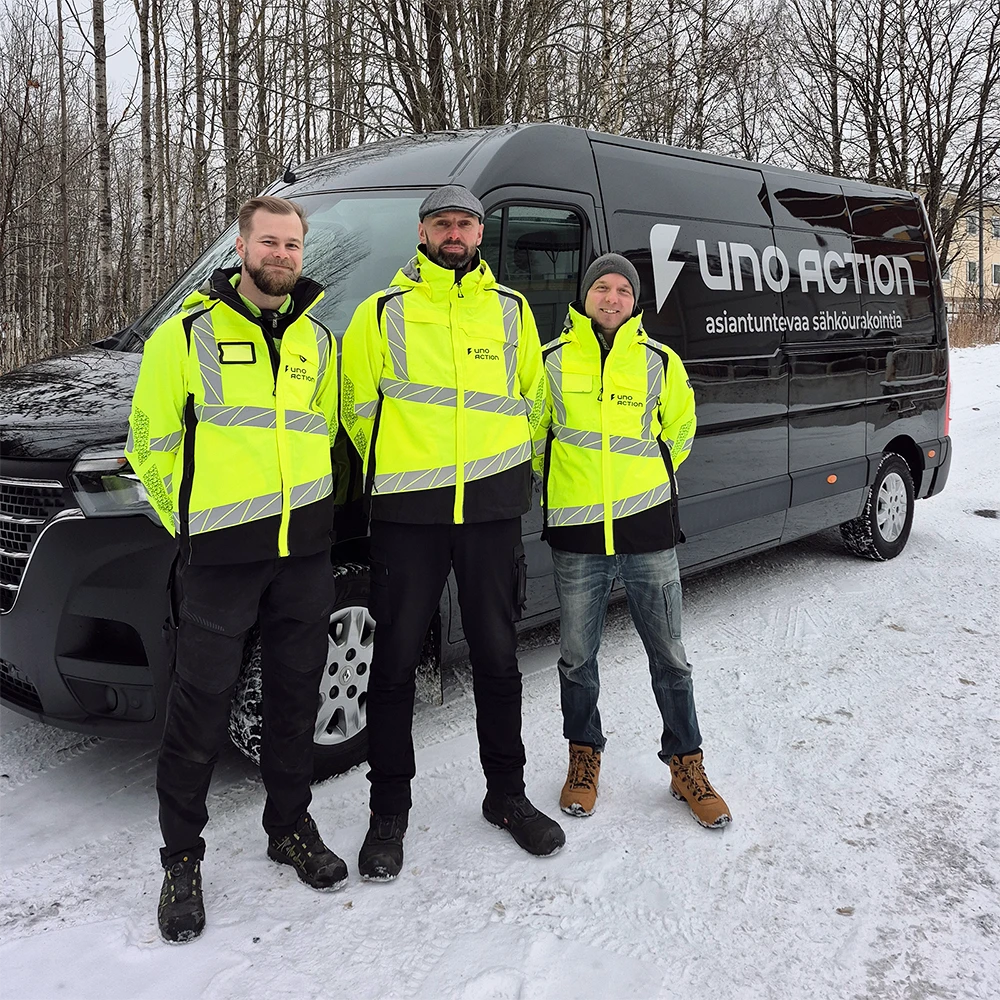 Uno Actionin Antti, Timo ja Teemu hymyilevät kuvassa ja katsovat kameraan ulkoilmassa, yrityksen pakettiauton edessä.